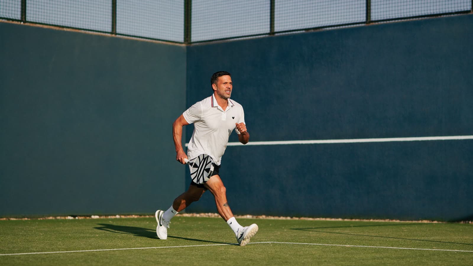Padel player in their forties stretching at the back of the court